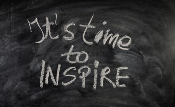 Schwarze Tafel auf der mit weißer Kreide "It's time to inspire" geschrieben steht.