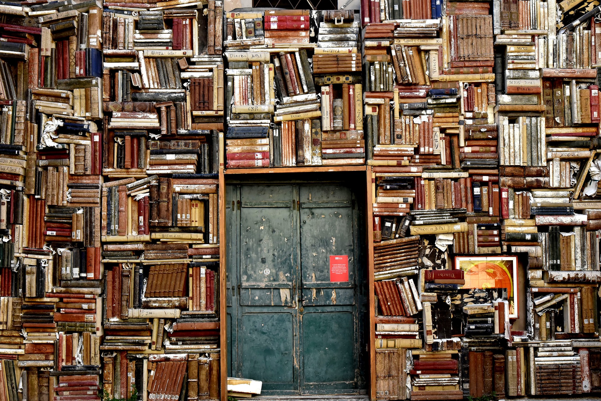 Eine Bücherwand voller alter Bücher mit einer Tür in der Mitte.