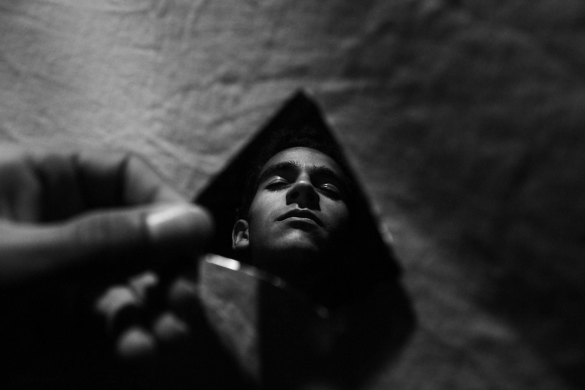 Ein Schwarz-Weiß-Foto eines Mannes, der sich in einer Spiegelscherbe betrachtet.