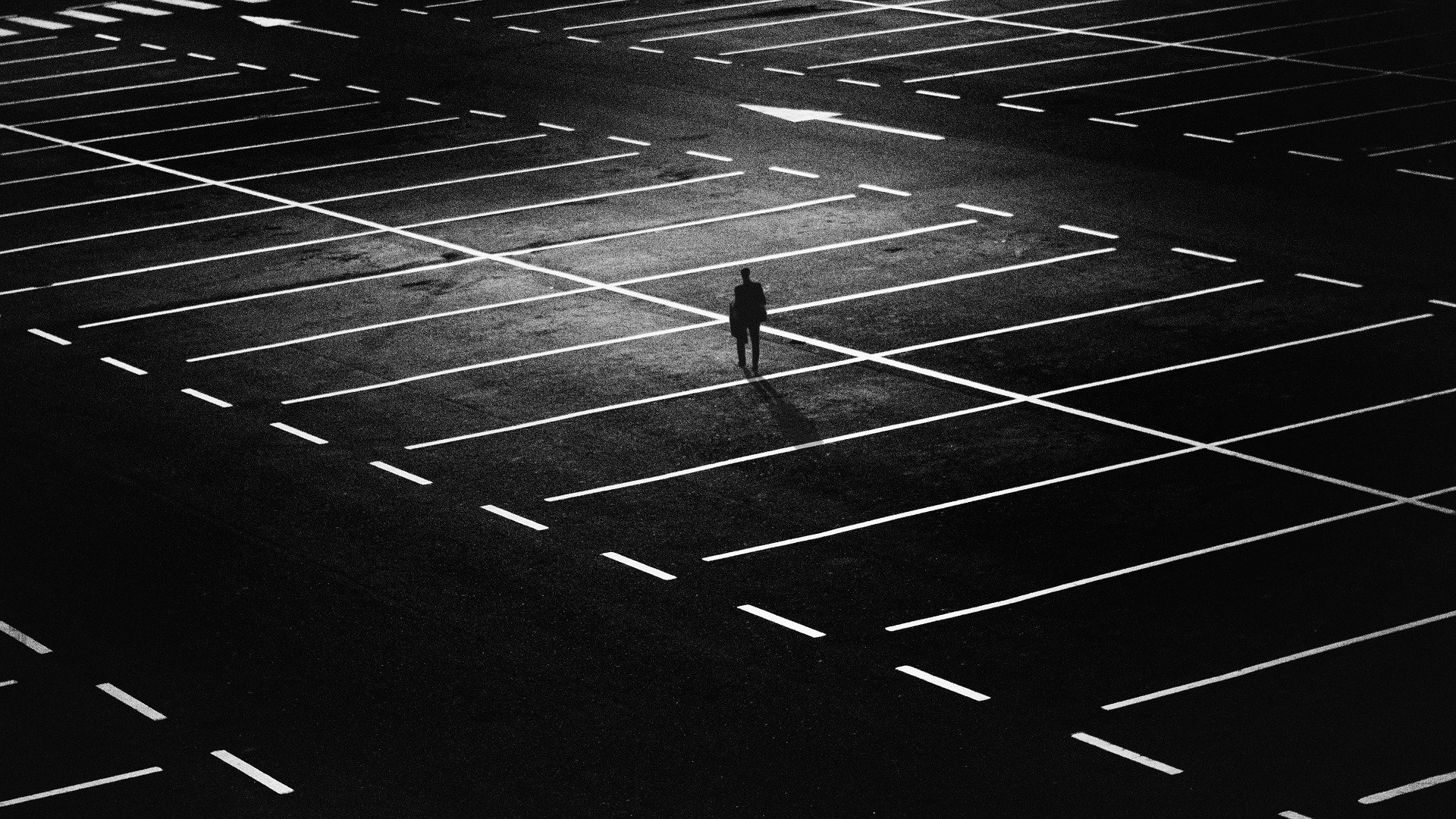 Ein Schwarz-Weiß-Foto einer Person, die auf einem Parkplatz steht.