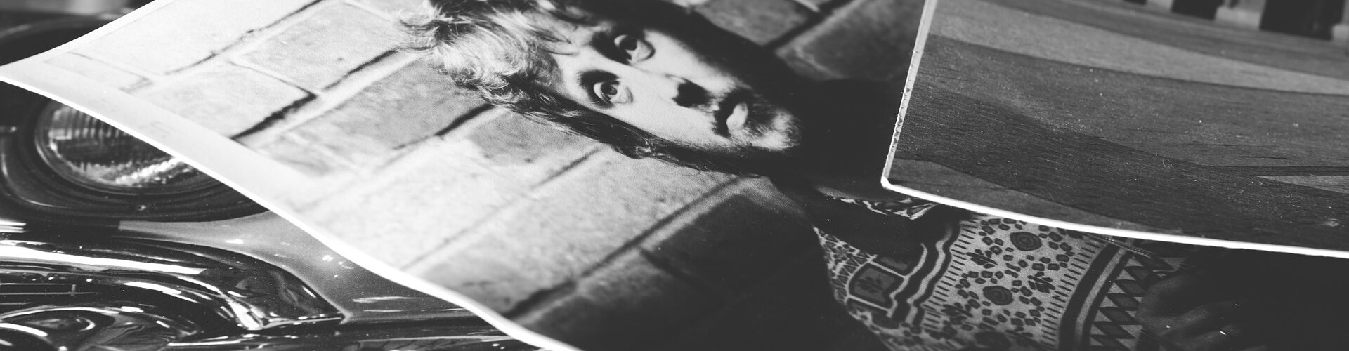 Drei Schwarz-Weiß-Fotos liegen übereinander. Das Porträt eines Mannes und Ausschnitte eines Autos und eines Gebäudes. Die Fotos haben einen leicht gewellten Rand.