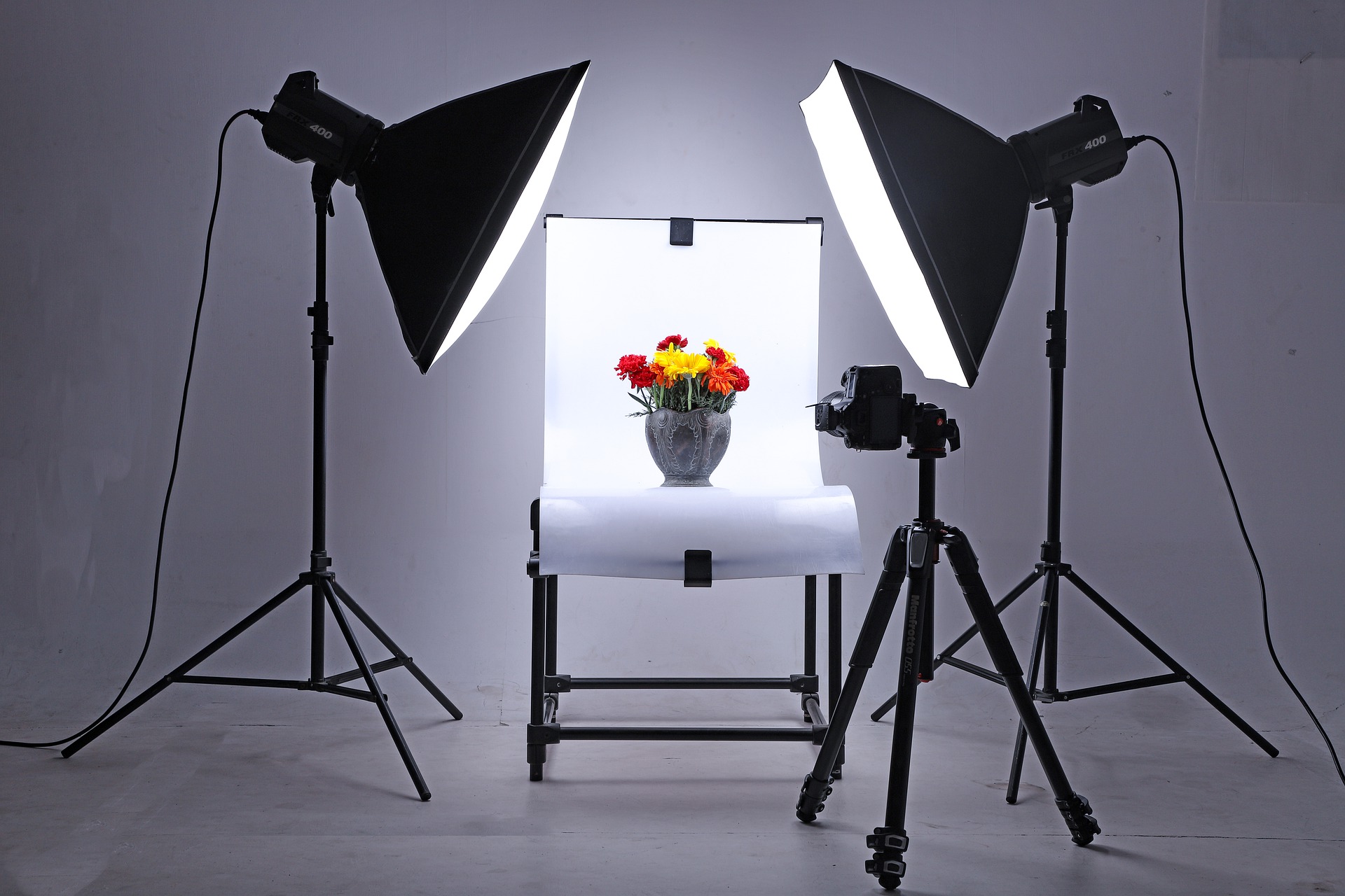 Ein Fotostudio mit einem Leuchttisch, auf dem eine Vase mit Blumen steht. Links und rechts zwei Scheinwerfer mit Lichtboxen.