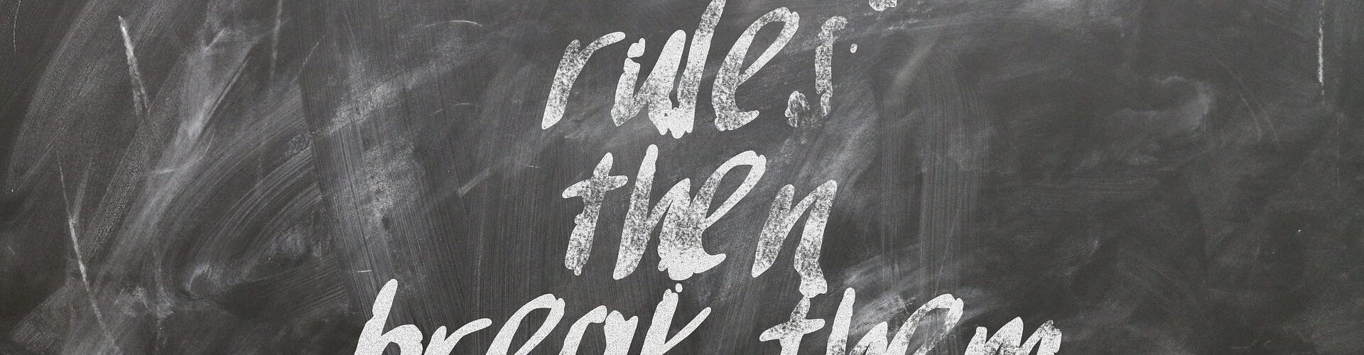 Eine schwarze Kreidetafel mit der Aufschrift: "First learn the rules then break them".