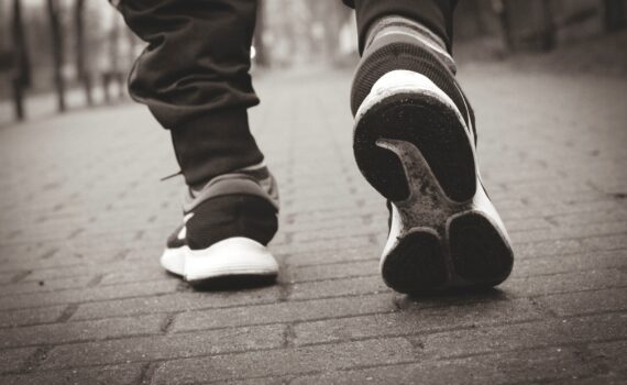 Die Turnschuhe einer Person, die einen gemauerten Gehweg hinuntergeht.