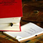 Ein dickes rotes Buch zur deutschen Rechtspraxis auf einem Tisch. Darunter eine hantschriftliche Notiz, in der es um Bildrechte und Lizenzen geht.