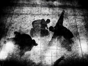 Die Silhouetten zweier Personen bei einem Judowurf auf einer Tatami-Matte, aufgenommen mit einem kontrastreichen Schwarzweißfilter.