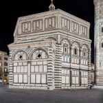 Das Baptisterium von S. Giovanni in Florenz ist nachts beleuchtet und zeigt sein charakteristisches Äußeres aus weißem und grünem Marmor mit geometrischen Mustern. (KI generierte Beschreibung)