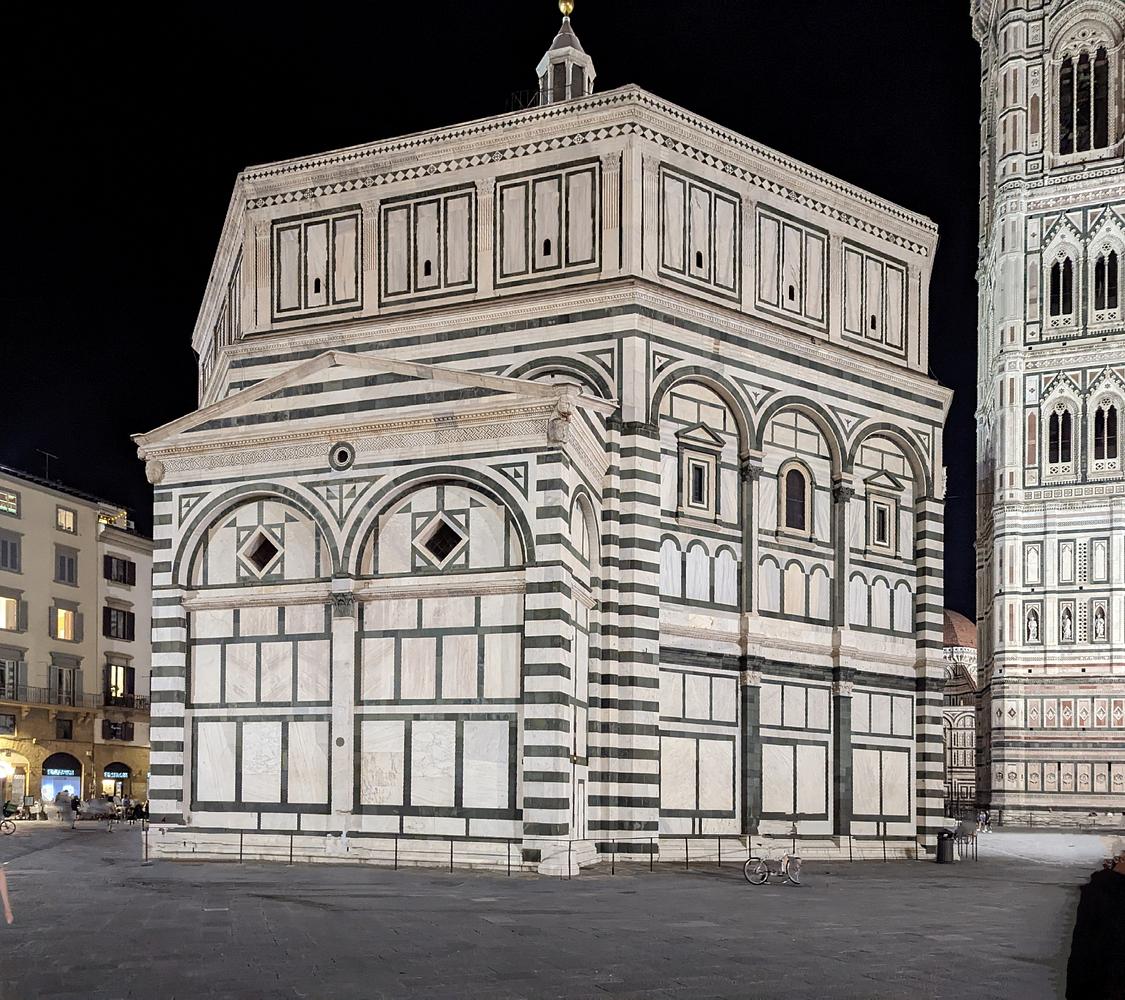 Das Baptisterium von S. Giovanni in Florenz ist nachts beleuchtet und zeigt sein charakteristisches Äußeres aus weißem und grünem Marmor mit geometrischen Mustern. (KI generierte Beschreibung)