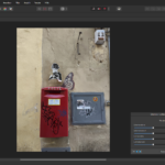 Roter Briefkasten an einer Wand mit Graffiti- und Schmetterlingsverzierungen, neben einem grauen Sicherungskasten. (KI generierte Beschreibung)