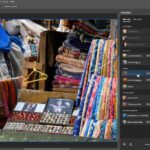 Bild eines Straßenmarktstandes mit gefalteten Stoffen und einer Auswahl an Schmucksets. (KI generierte Beschreibung)