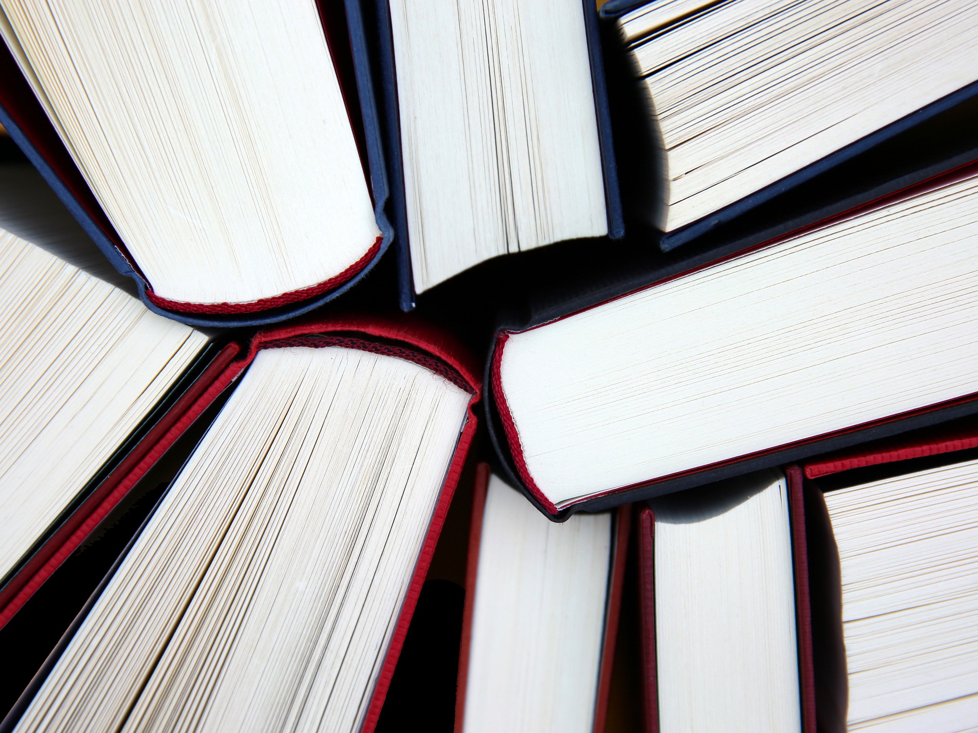 Eine Nahaufnahme einer Sammlung gebundener Bücher, die kreisförmig angeordnet sind, mit dem Rücken nach innen und den Seiten nach außen. (KI generierte Beschreibung)