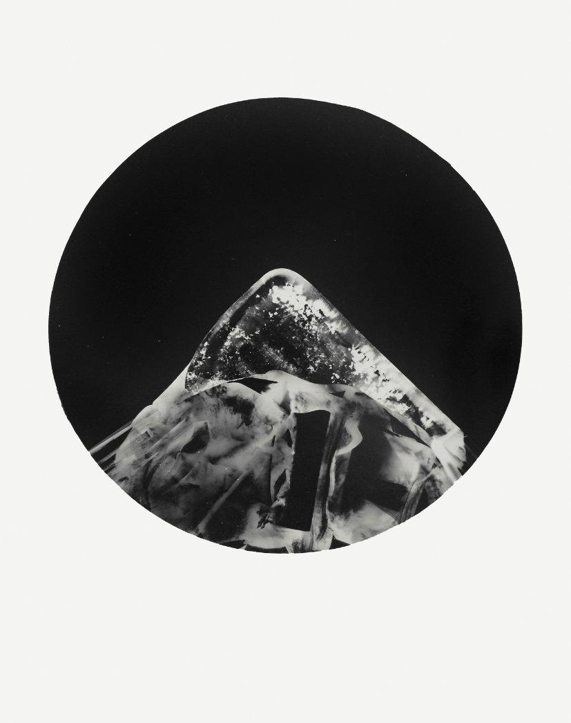 Monochromes abstraktes Bild, das einen kreisförmigen Rahmen mit einer dreiecksähnlichen Form darin zeigt, mit Texturen und Mustern. (KI generierte Beschreibung)