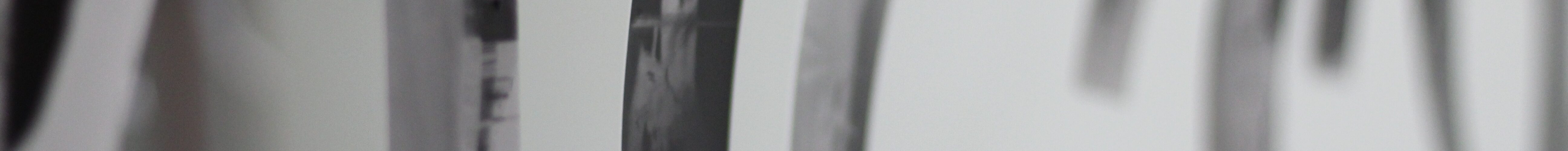 Schwarzweißfotos hängen an einer Leine mit bunten Wäscheklammern vor unscharfem Hintergrund. (KI generierte Beschreibung)