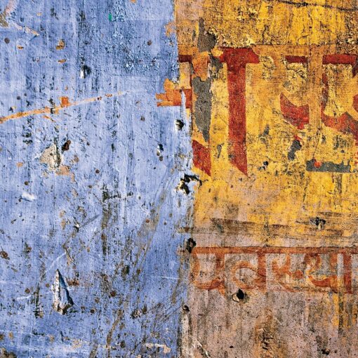 Verwitterte Wand mit verblasster blauer Farbe auf der linken Seite und gelber Farbe mit roter und orangefarbener Schrift auf der rechten Seite. (KI generierte Beschreibung)