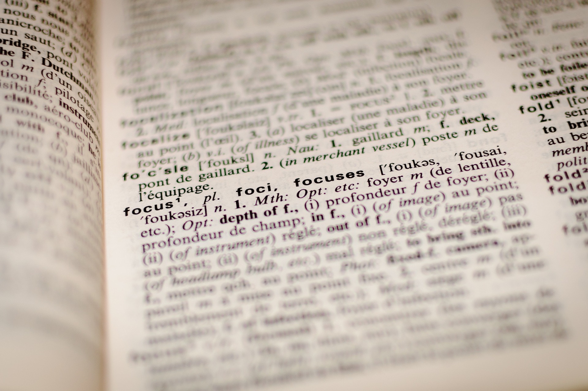 Nahaufnahme einer aufgeschlagenen Wörterbuchseite mit dem Schwerpunkt auf der Definition von „Fokus“, wobei der benachbarte Text leicht unscharf ist. (KI generierte Beschreibung)