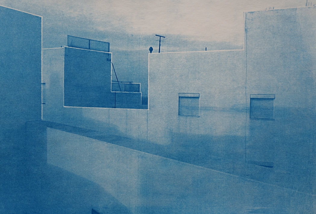 Ein monochromatisches Bild in Blautönen von Stadtdächern und Gebäudefassaden. Geometrische Formen sind markant, mit minimalen Details und einem klaren Himmel im Hintergrund. (KI generierte Beschreibung)