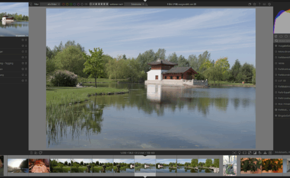 Ein Pavillon im traditionellen Stil steht an einem spiegelnden Teich, der von Bäumen umgeben ist, mit blauem Himmel und Wolkenfetzen über dem Kopf, dargestellt in einer Fotobearbeitungssoftware. (KI generierte Beschreibung)