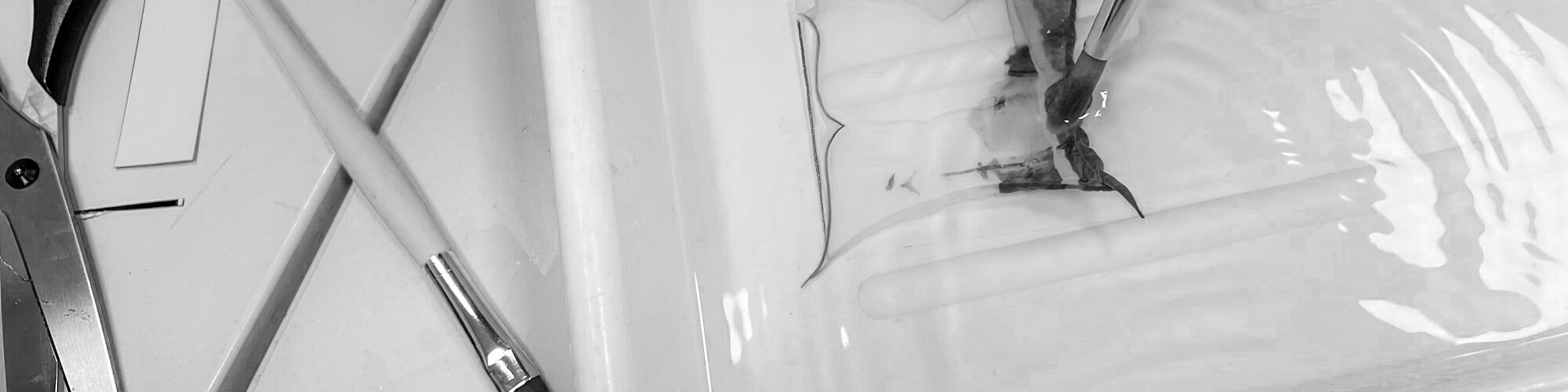 Mit einem Pinsel wird ein dünner Film auf das Wasser in einer Schale aufgetragen, während eine Schere und ein weiterer Pinsel in der Nähe auf der Oberfläche liegen. (KI generierte Beschreibung)