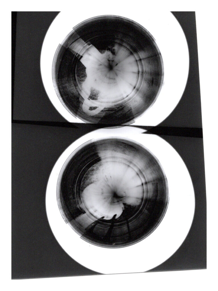 Monochromes Bild von zwei runden Objekten mit abstrakten, wirbelnden Schwarz-Weiß-Mustern, die auf einer reflektierenden Oberfläche platziert sind. (KI generierte Beschreibung)