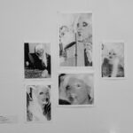 Fünf monochrome, verzerrte Fotoporträts einer Person mit langen Haaren sind in einer Gruppe an einer weißen Wand ausgestellt. (KI generierte Beschreibung)